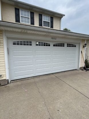 Garage door service technician diagnosing spring and opener strain in Dayton Ohio